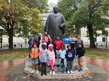 Fifth-grades huddled around a statue